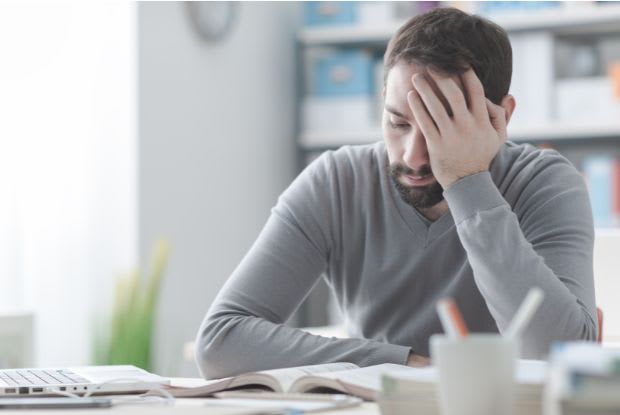 a man with a headache sitting at his desk
