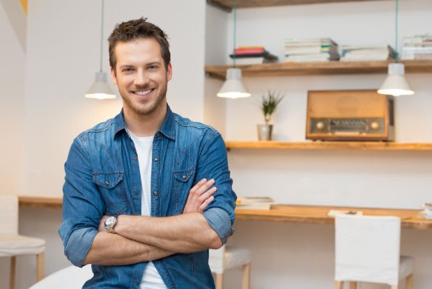a happy man standing with his arms crossed