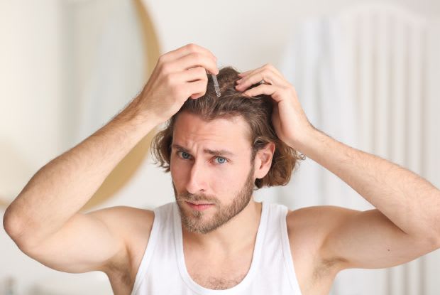a man applying hair growth solution to his scalp
