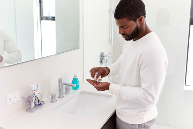 man taking a tablet in the bathroom