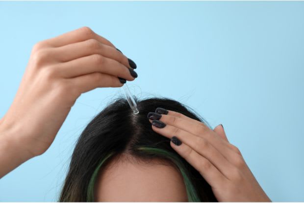 a woman applying hair serum for hair growth