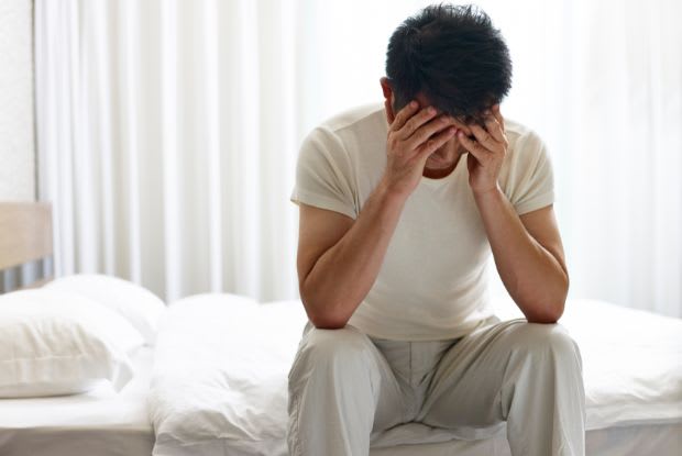 a frustrated man sitting in bed