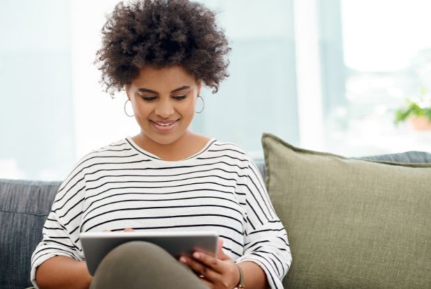 A woman sitting on the couch and using her tablet