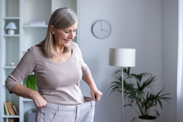 An elderly woman wearing pants that are too big