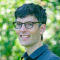 Headshot of Koos in front of a natural background