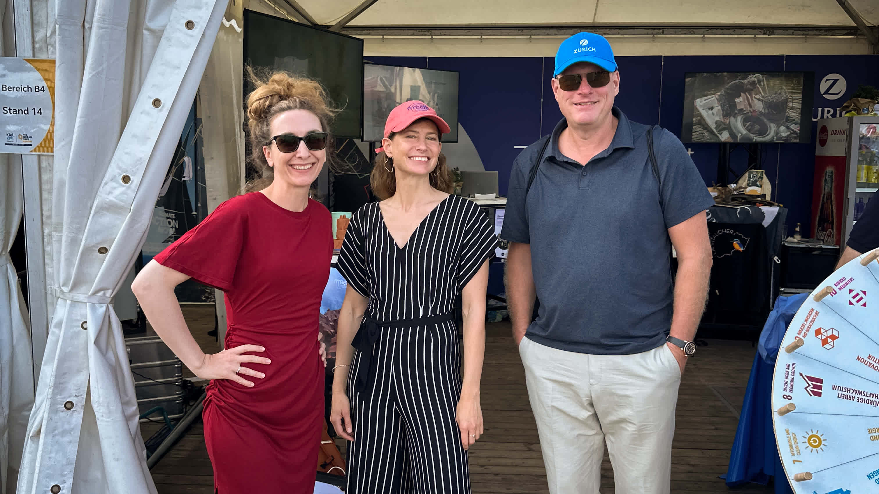 Ruth von Heusinger, Ulrike Pfreundt, and Carsten Schildknecht are standing in front of the Zurich tent at Ocean Live Park, smiling at the camera.