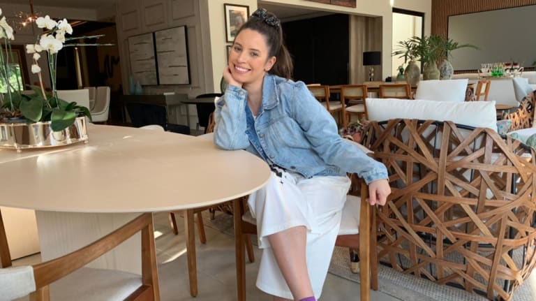 Na foto, a arquiteta está encostada na mesa oval de laca branca.