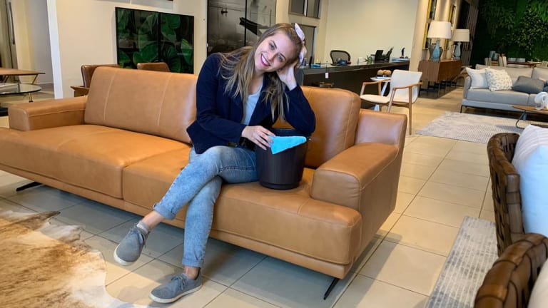 A jornalista está sentada em um jornal de couro marrom, com o cotovelo apoiado em cima de um balde.