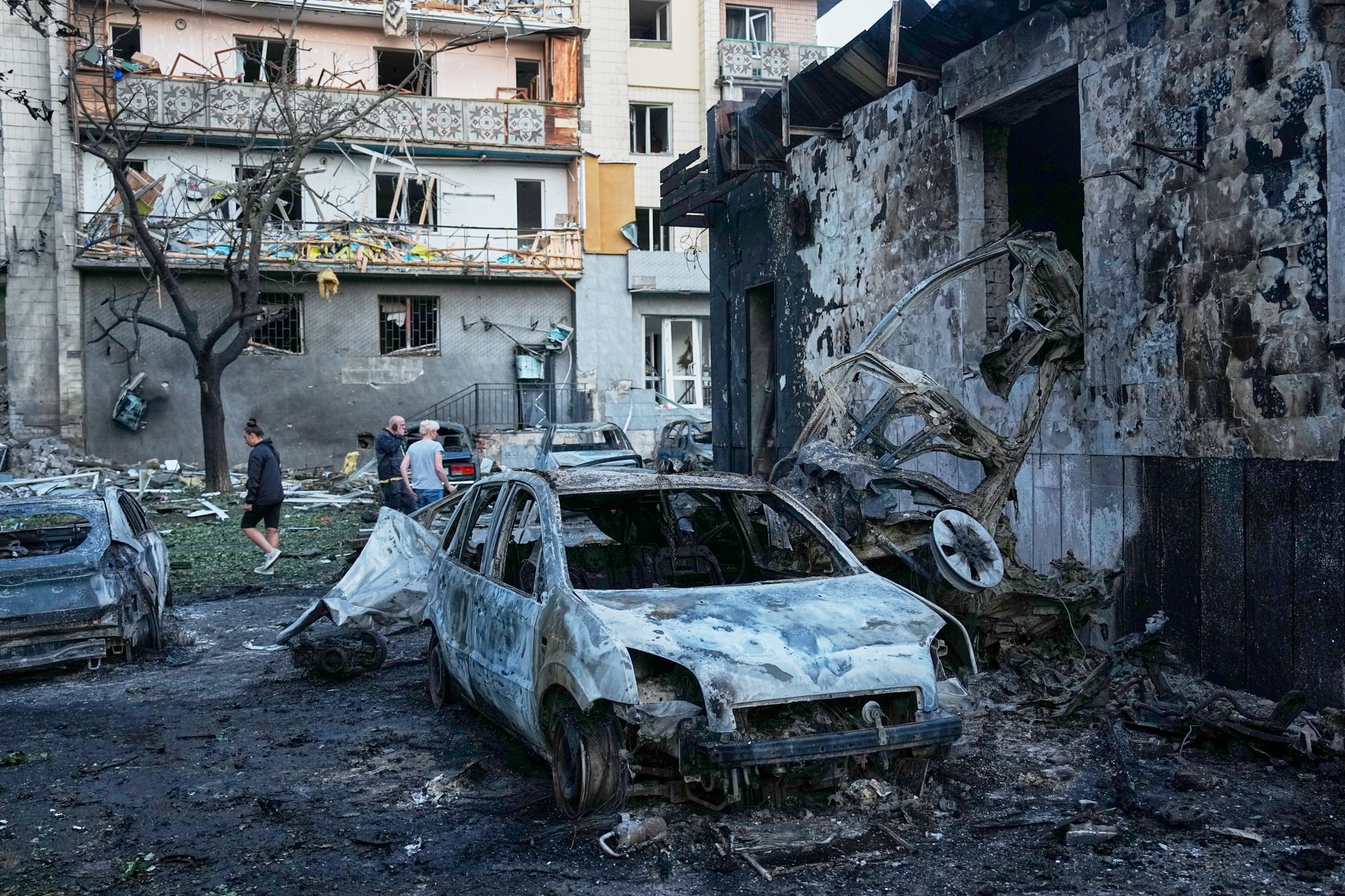 Beschädigte Stadtstraße in Kiew nach einem nächtlichen Angriff, Einsatzkräfte im Hintergrund, realistischer Fotojournalismus-Stil