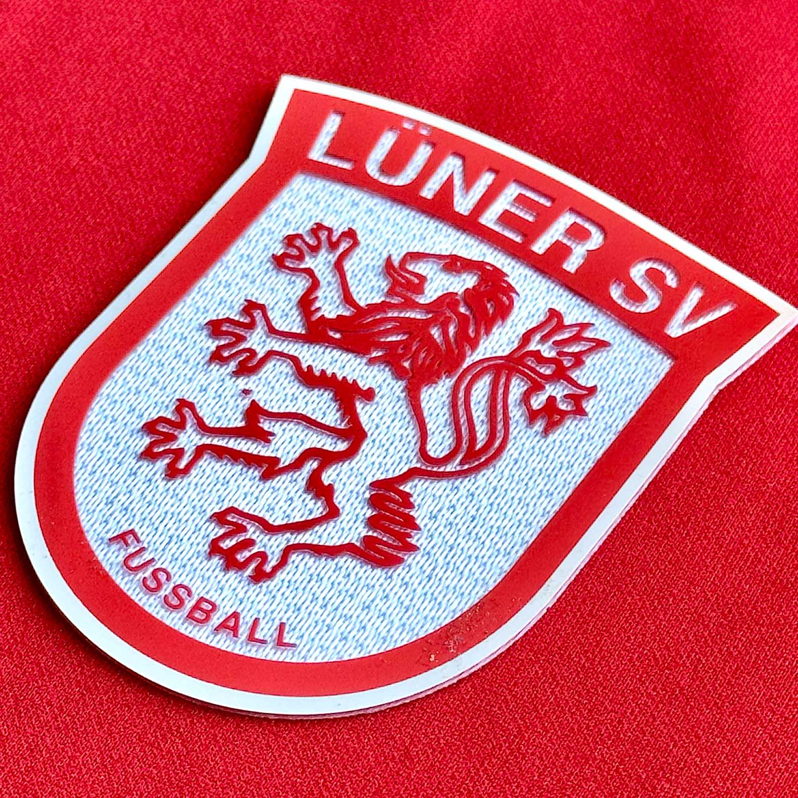 3D-Vereinswappen aus TPU auf einem Trikot – plastische Optik mit fühlbarer Tiefe und mehreren Farbschichten. Premium-Veredelung von SportBros aus Lünen.
