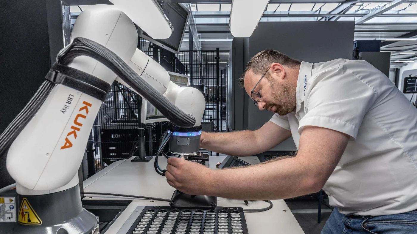 Engineer teaching the KUKA LBR iisy cobot by physically guiding its arm, no code required for basic path programming