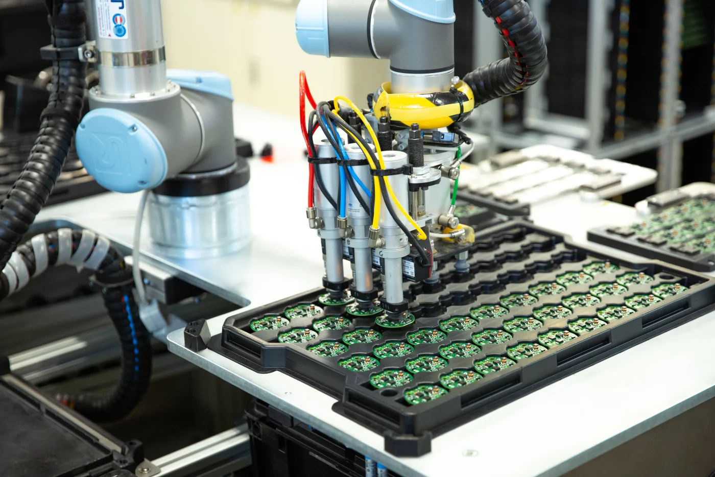 Universal Robots collaborative robot arm versus humanoid robots: cobot working alongside a human operator in electronics manufacturing, humanoid robots vs cobots in action