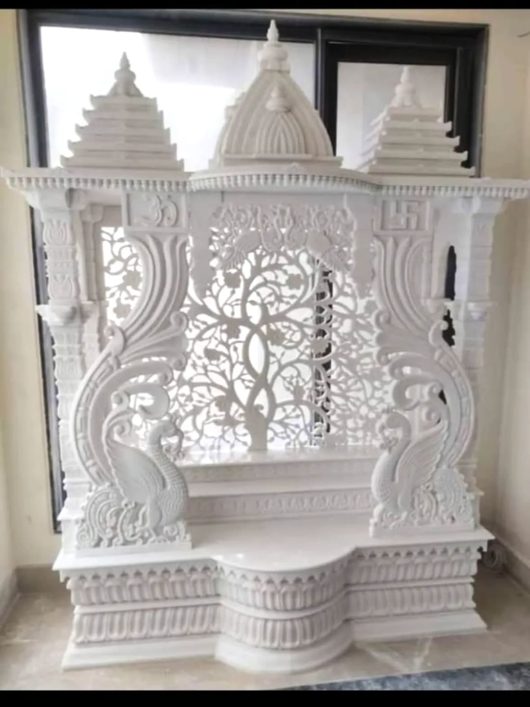 Marble mandir with carved pillars and a stepped dome, in traditional temple proportions