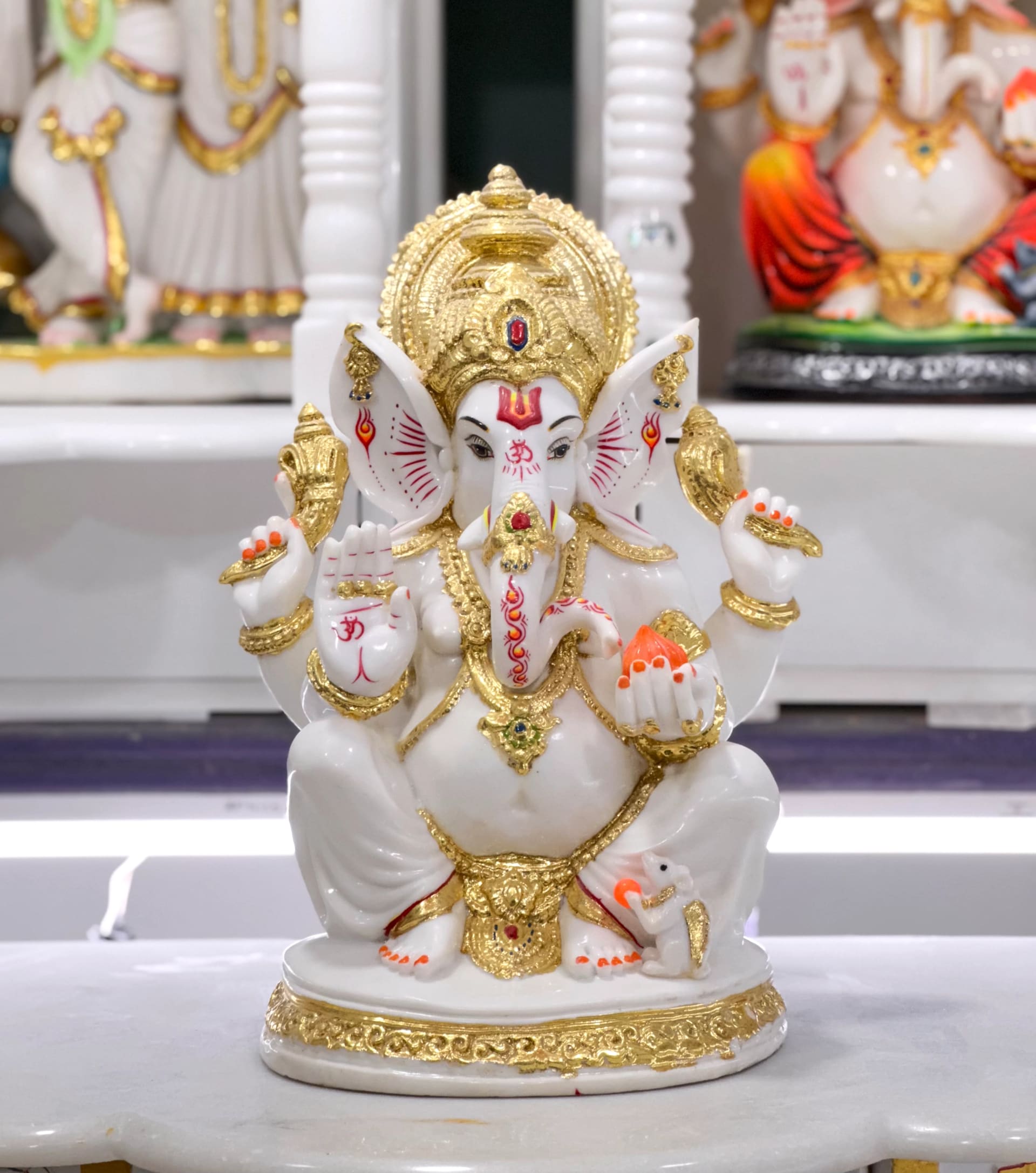 Ganesha murti in white Italian marble, seated with one hand raised in blessing