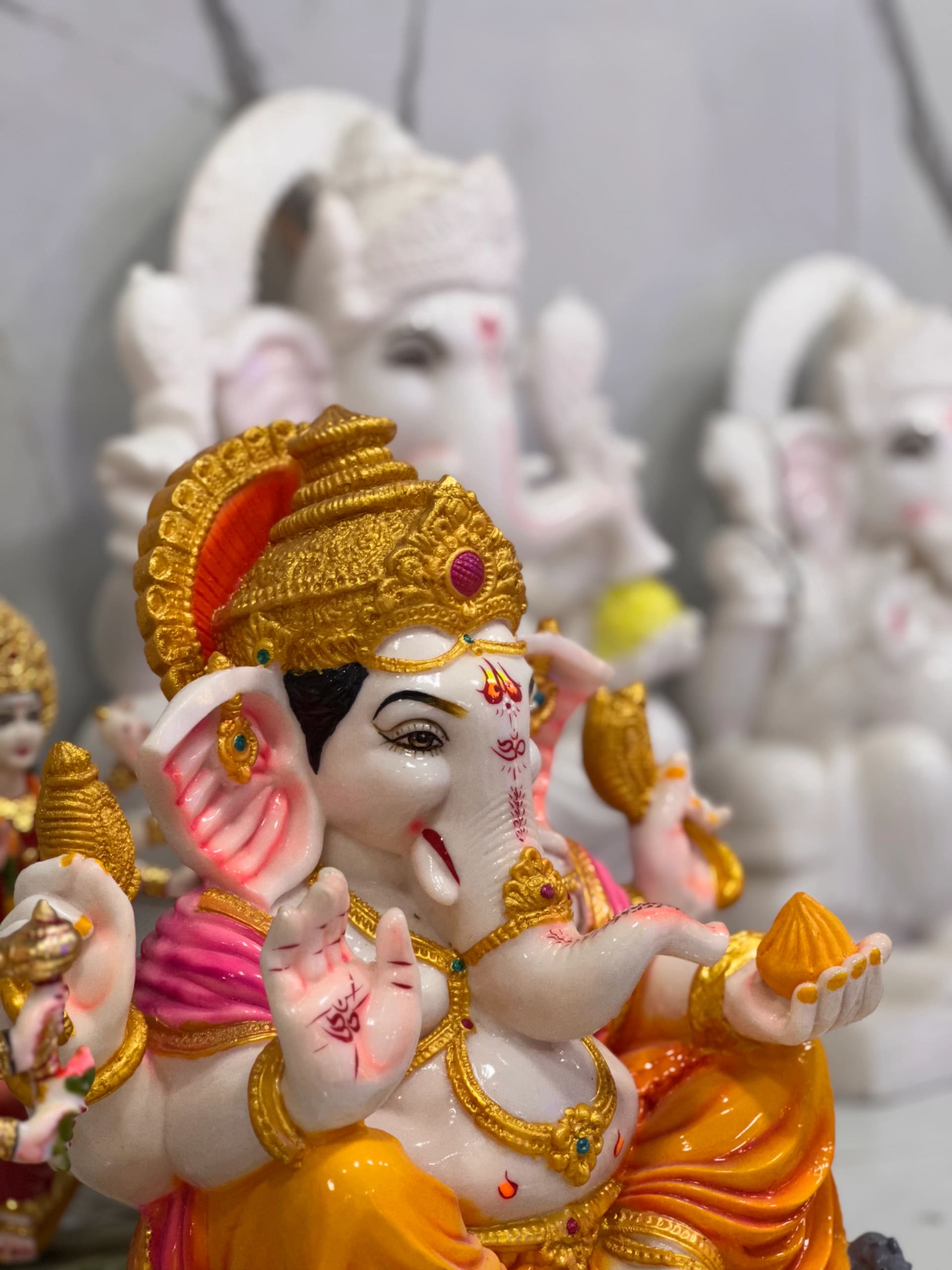 Ganesha murti in marble, crown and robes finished in red and gold