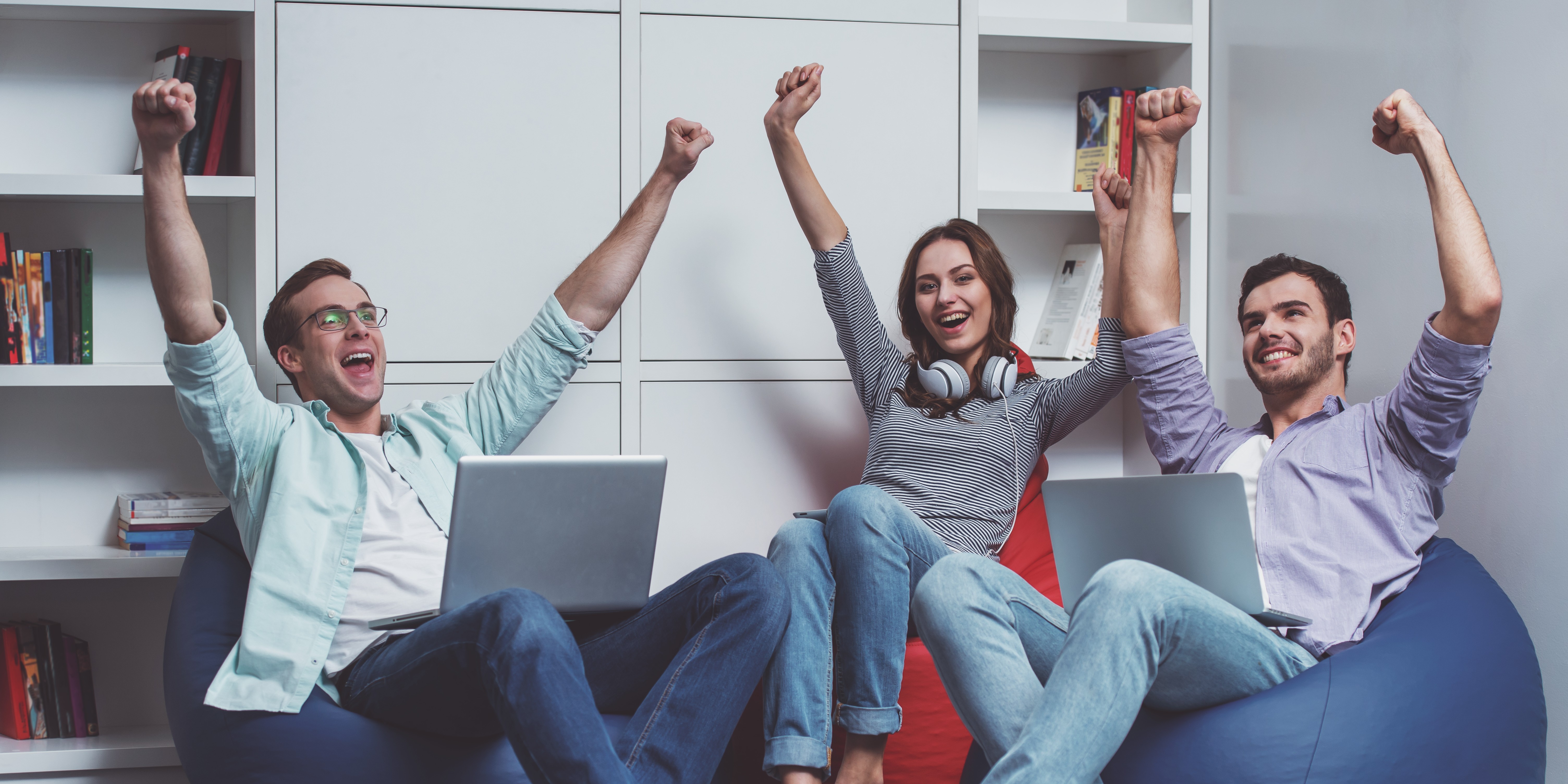 A group of young professionals cheering with their laptops after completing a MockWin peer-to-peer AI mock interview challenge