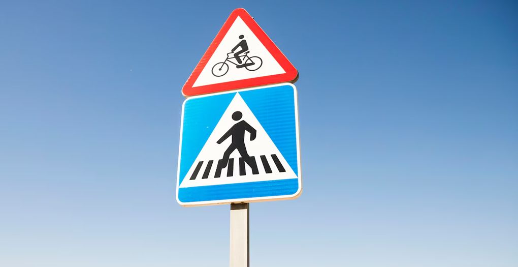 A street sign with a man on a bicycle crossing the road.