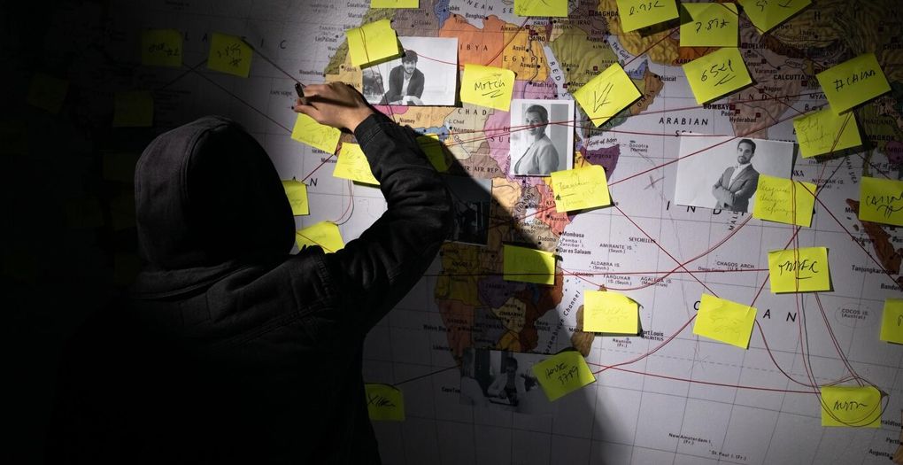 A person in a hoodie marking a map with yellow colored sticky notes.