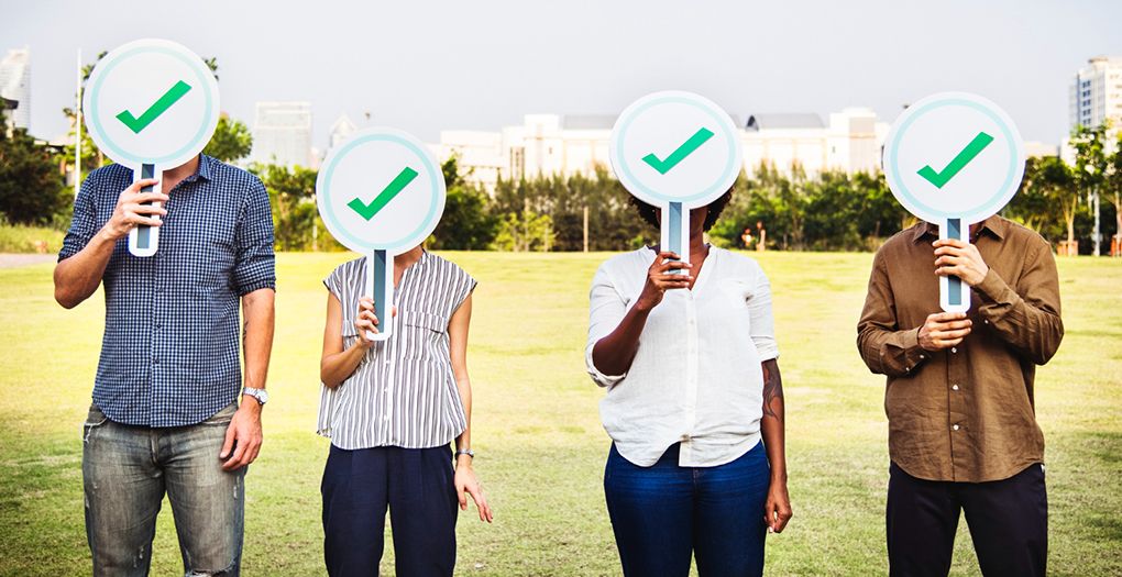 Four people showing approval by holding signs with check marks.