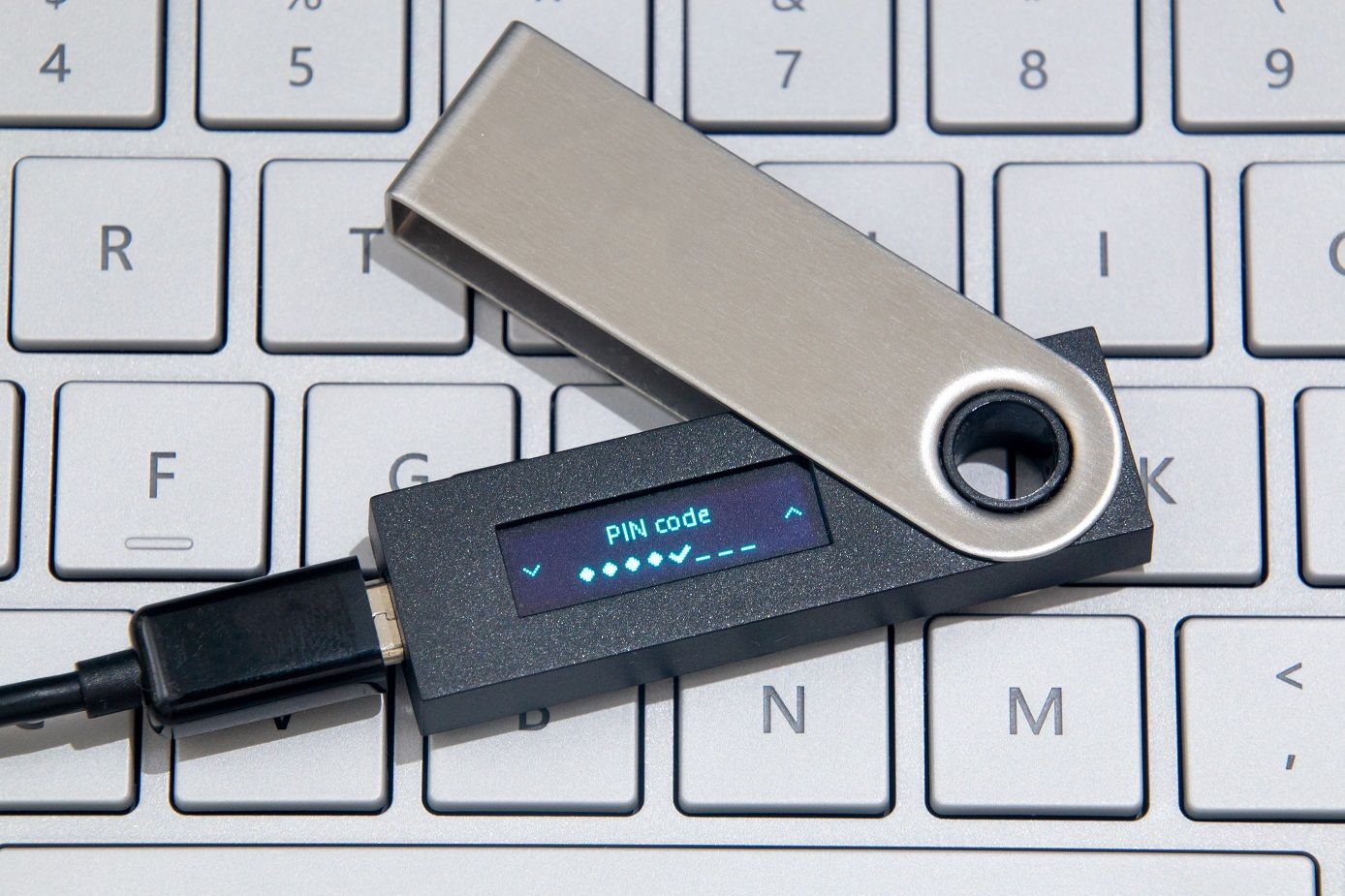 A hardware wallet for crypto lying on a laptop keyboard