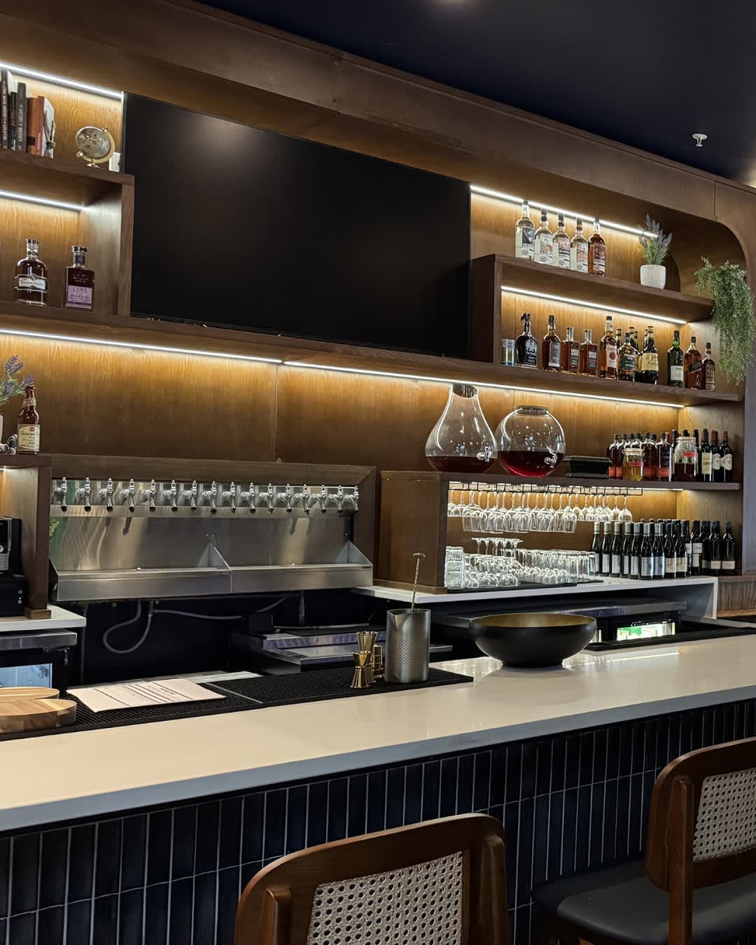 Main bar at Champagne Velvet Proper Kitchen & Bar — wood-paneled back bar, lit liquor display, beer taps, glassware