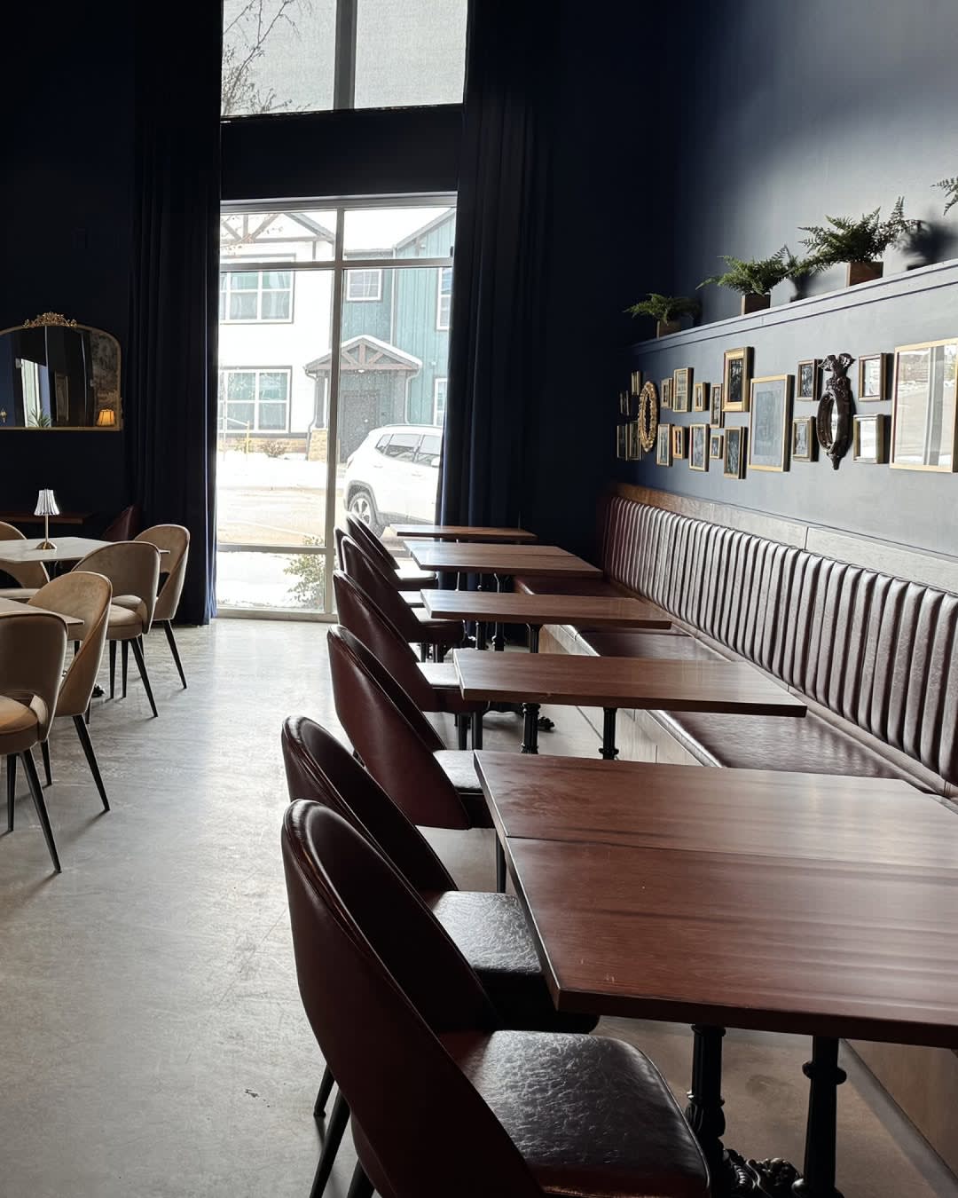 Champagne Velvet Proper Kitchen & Bar dining room with navy walls, banquette seating, and a curated gallery wall