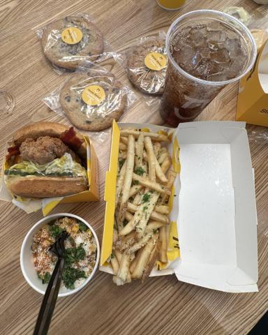 Starbird Chicken food spread with sandwich, fries, and craft soda