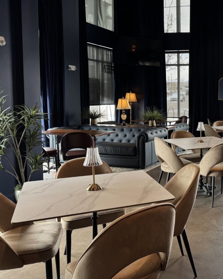 Champagne Velvet Proper Kitchen & Bar lounge area with Chesterfield-style tufted leather seating, marble bistro tables, and table lamps