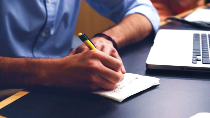 VHodná povolání pro znamení lev muž u psacího stolu s tužkou a papírem a notebookem