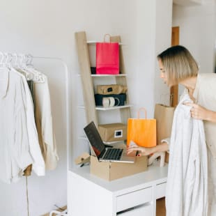 A woman is working on her laptop in her boutique shop