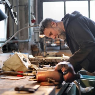 A smiling tradesman working in his workshop.