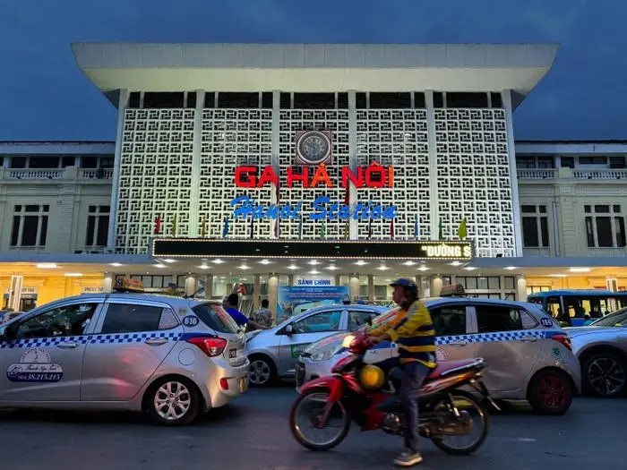 Outside Hanoi Railway Station on busy road with cars and motorbikes