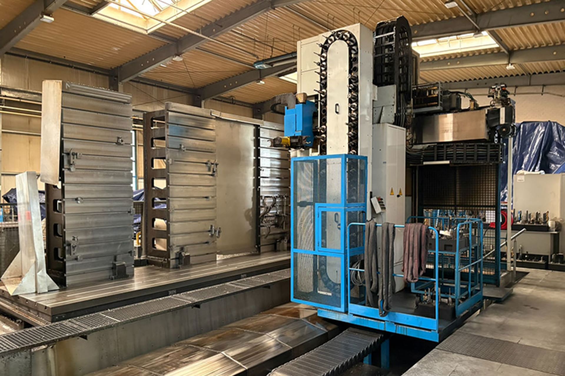 FPT SIRIO-M CNC travelling-column machine with large clamped workpieces and a blue operator platform in an industrial workshop