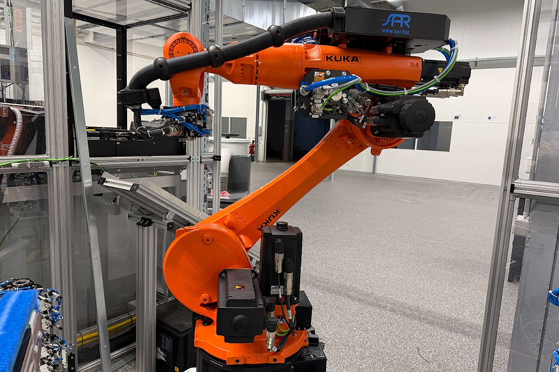 KUKA KR 22 R1610-2 /SEL handling robot with a gripper and hose package inside an enclosed automation cell.