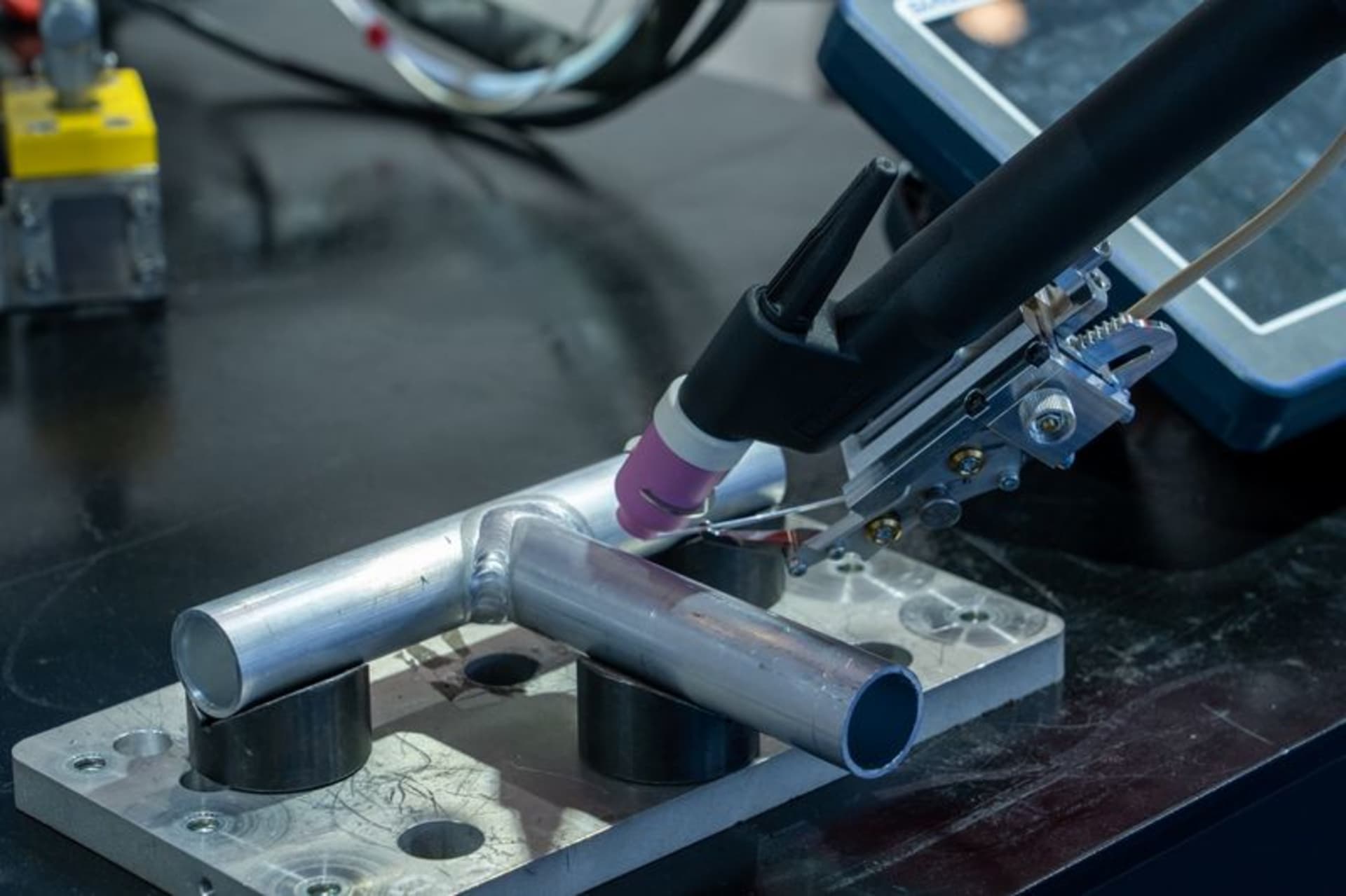 TIG welding torch with a separate wire feed positioned at clamped metal tubes