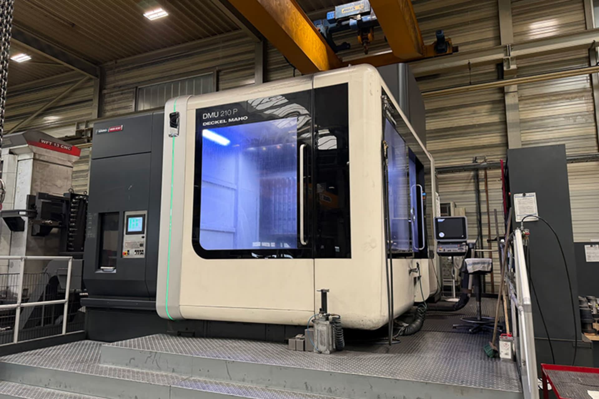 DMU 210 P CNC-Bearbeitungszentrum mit geschlossenem Maschinengehäuse, beleuchtetem Arbeitsraum und seitlichem Bedienpult