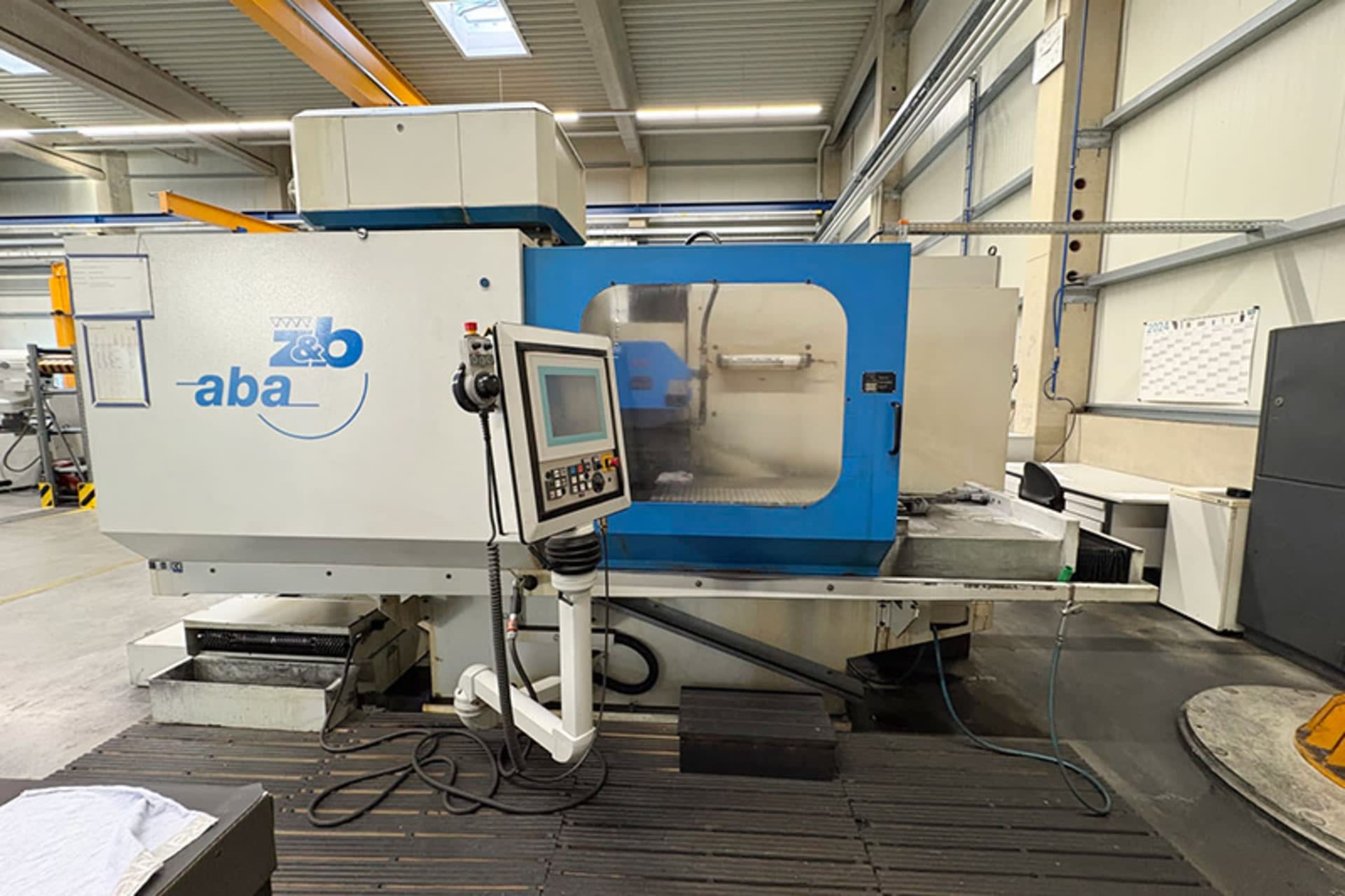 ABA EcoLine 1006A Flachschleifmaschine mit blauer Schutztür, Sichtfenster und Bedienpult vor dem Maschinengehäuse