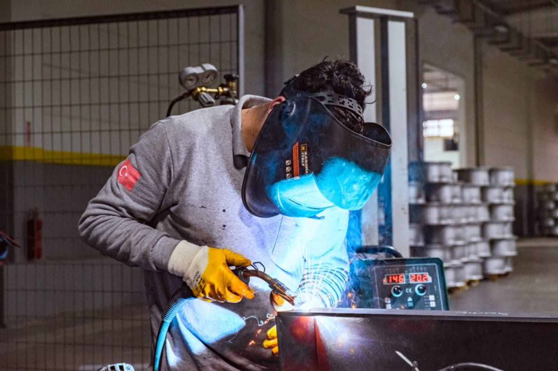 Schweißer mit Schutzhelm und Handschuhen beim MIG/MAG-Schweißen eines Metallbauteils