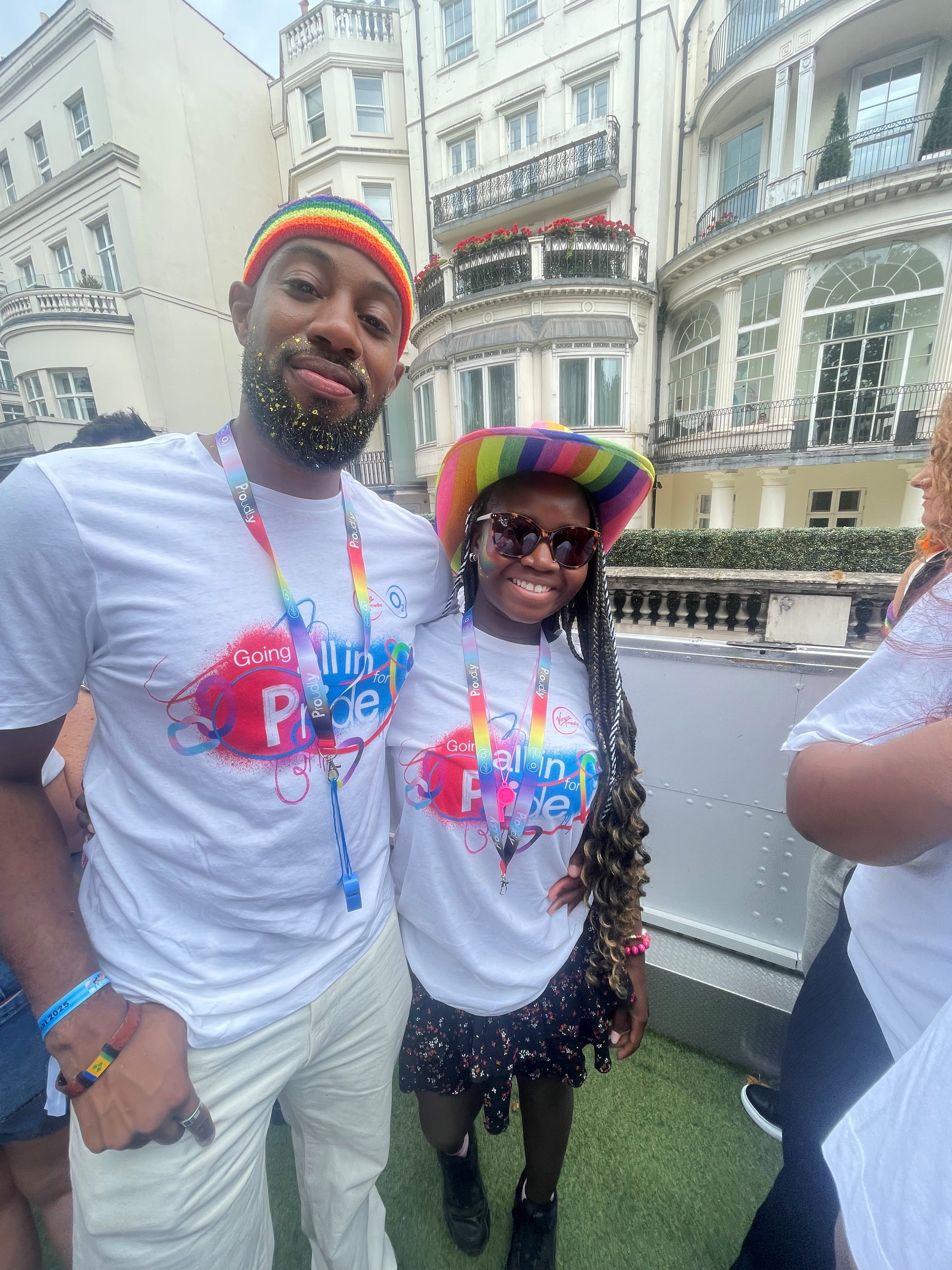 Picture of Katreece on the right and colleague on the left celebrating Pride wearing branded Virgin Media O2 colourful tops on a bus