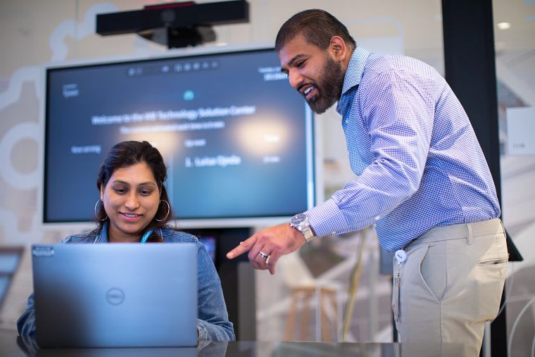 Two individuals looking at a laptop. 