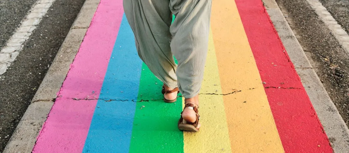 person walking on a street that has the LGBT flag painted on it