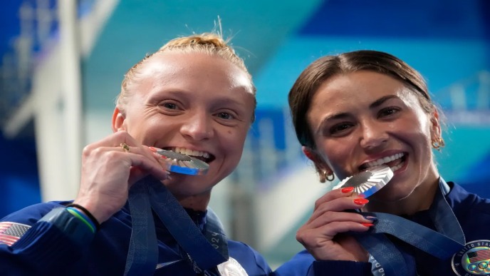 Synchronized Diving team USA biting Olympic Medal