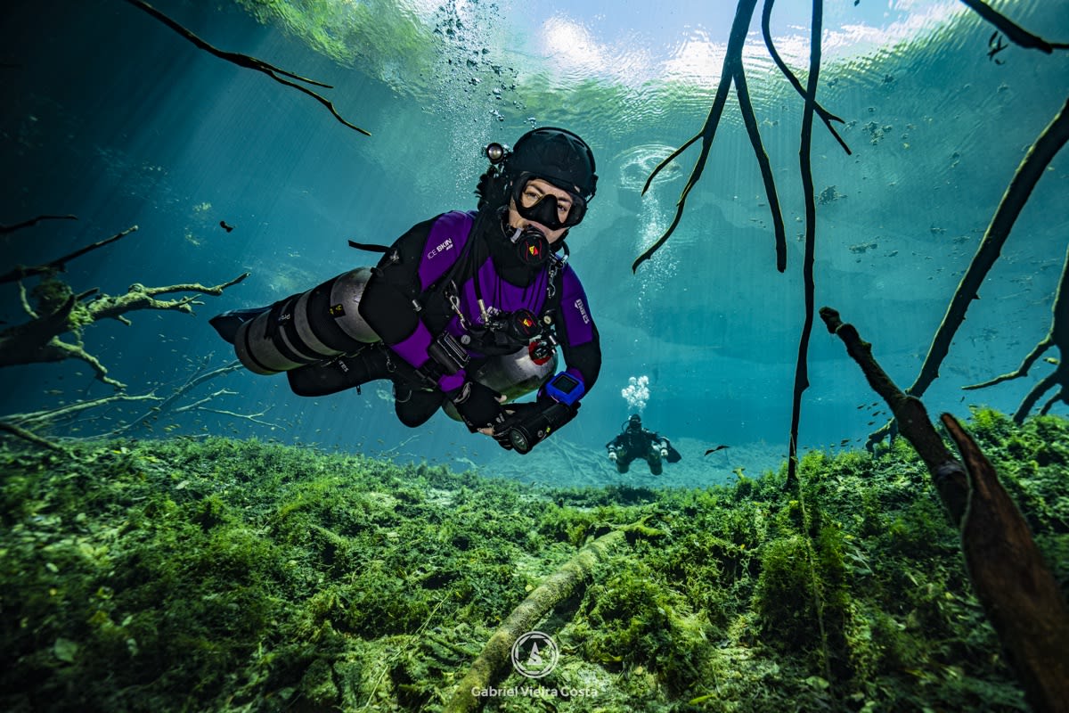 Mergulhadora sidemount no jardim verde de um cenote em Tulum
