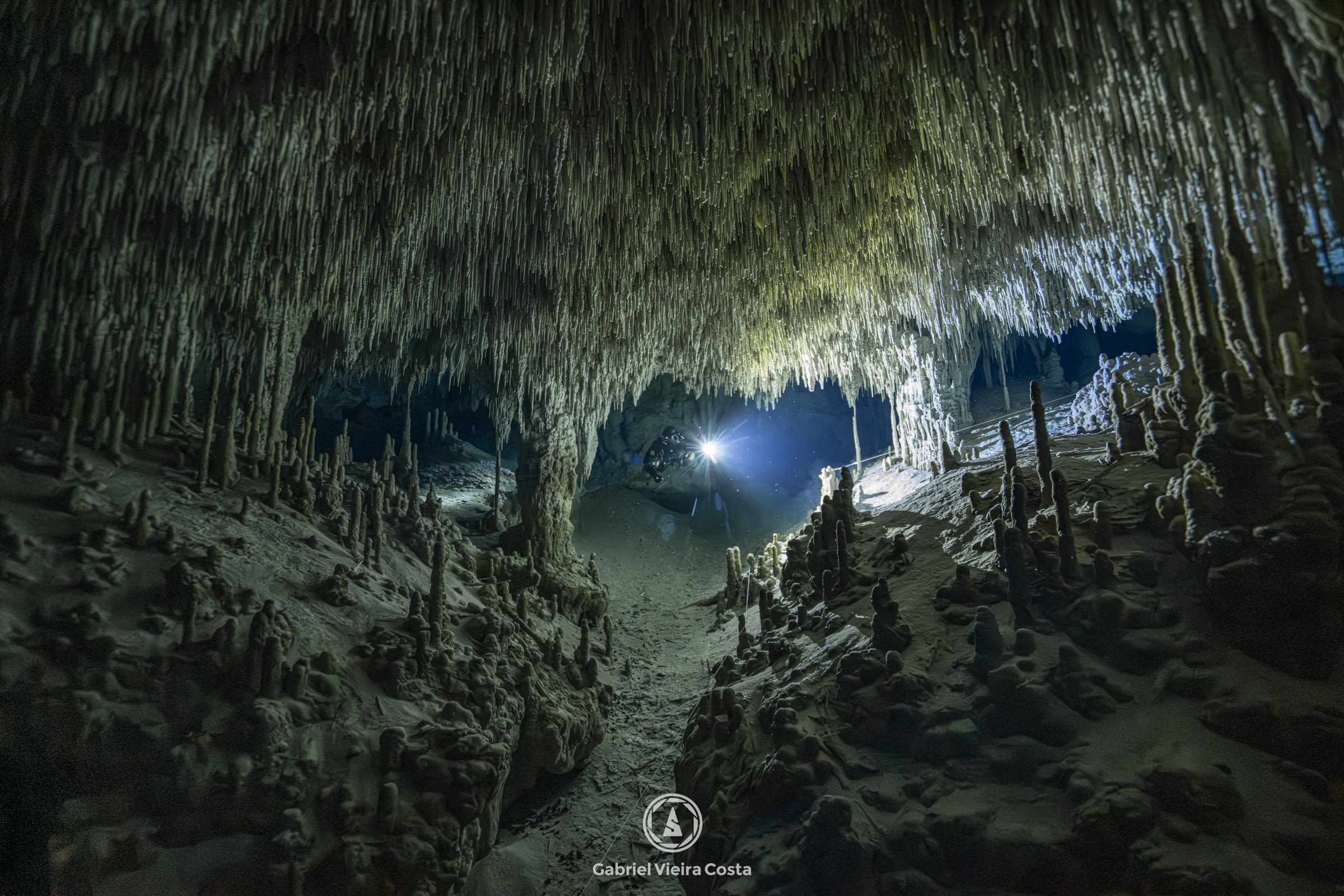 Salão de caverna com estalactites e luz de mergulhador em Tulum