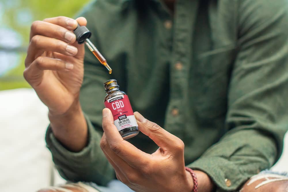 A man removes a dropper from a bottle of CBD isolate tincture