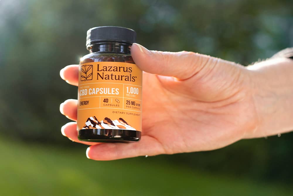 A robust hand holding a bottle of Lazarus Naturals CBD Capsules