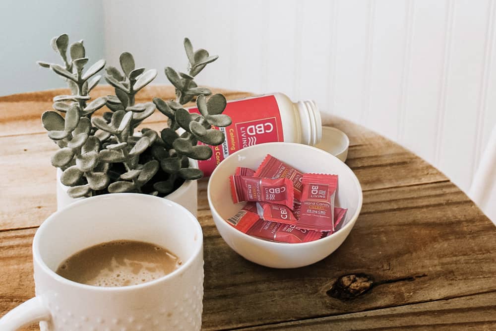 A bowl of delicious CBD lozenges beside a cup of coffee; we do not recommend this flavor combination, but you do you.