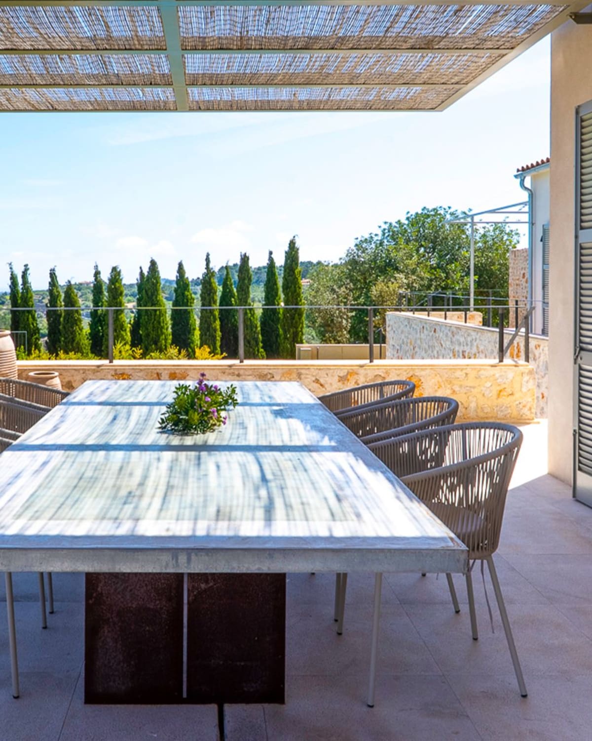 Der Esstisch auf der Terrasse, dahinter eine Reihe Zypressen, Finca Sant Llorenç