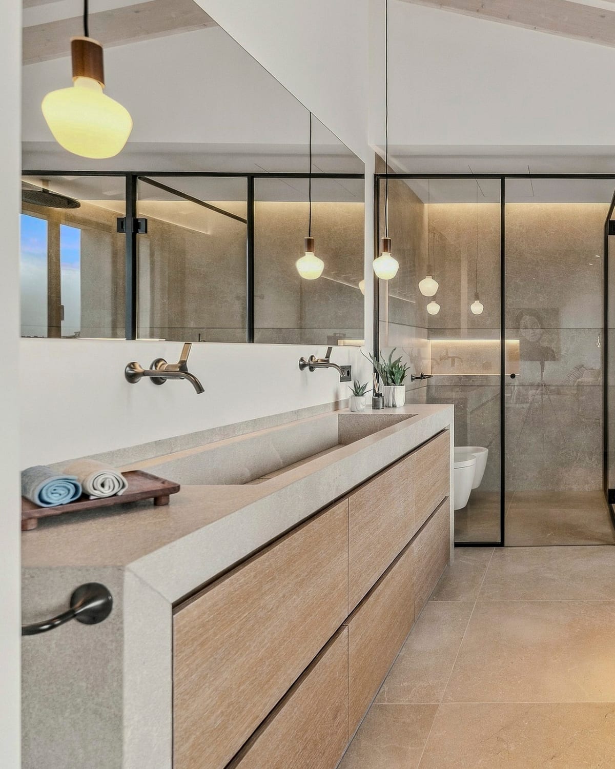 Ein Badezimmer mit freistehender Badewanne, langem Waschtisch aus Eiche und glasumwandeter Dusche, Santanyí III