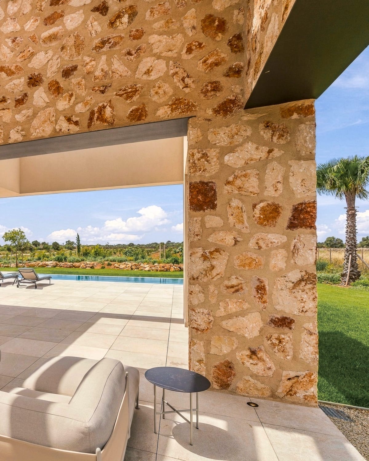 Eine überdachte Terrasse mit einem Sofa, die sich zum Pool und zum Rasen öffnet, Santanyí III